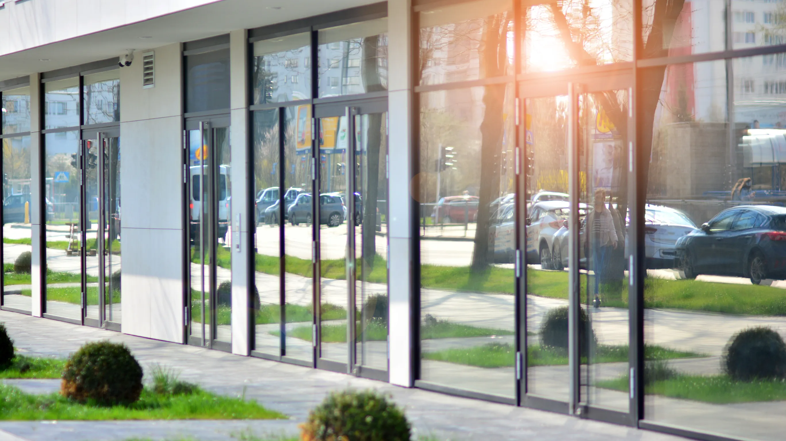 Local company in Orlando offers repair for sliding glass door with reflection of trees, grass, and parked cars on the windows.